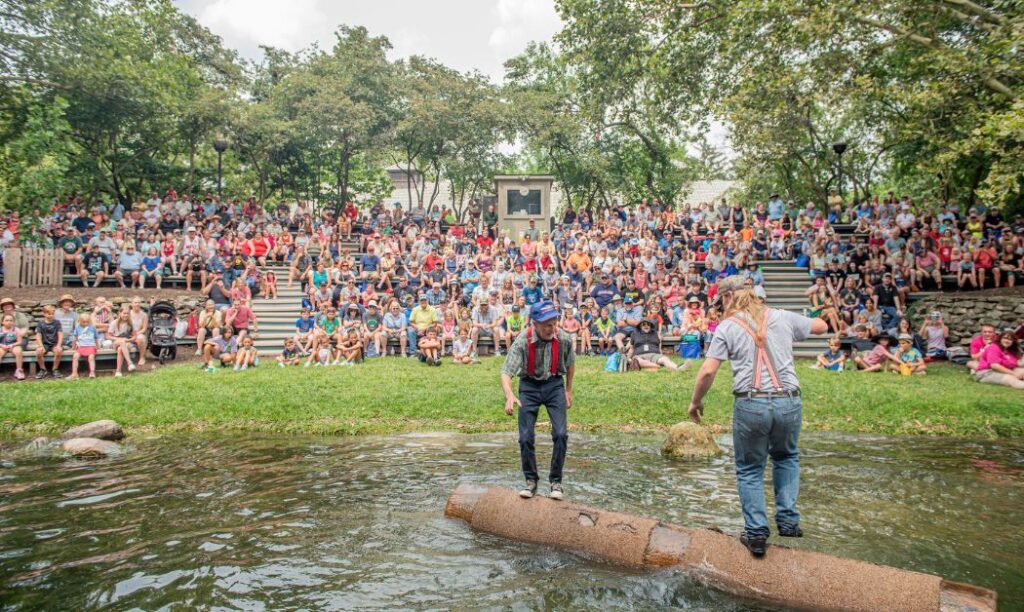 Two men competing in log rolling as a crowd watches at the Ohio State Fair