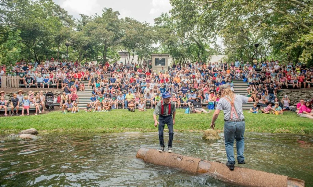 Two men competing in log rolling as a crowd watches at the Ohio State Fair