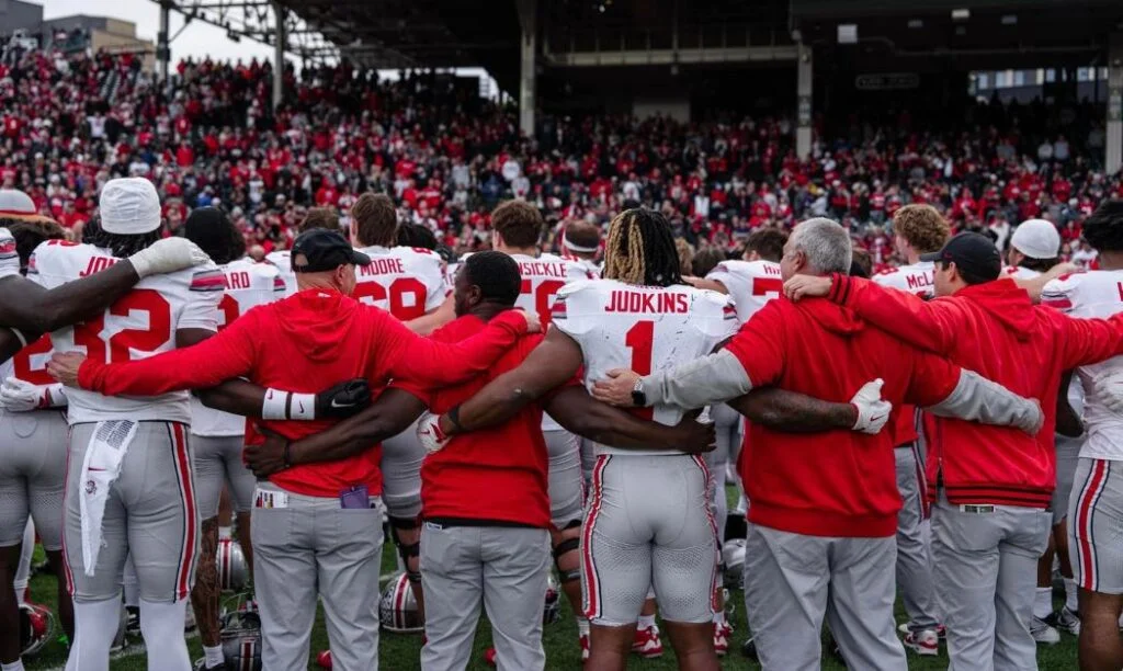 Ohio State players, coaches, and staff lock arms during Carmen Ohio after a victory vs. Northwestern at Wrigley Field in Chicago, Illinois.