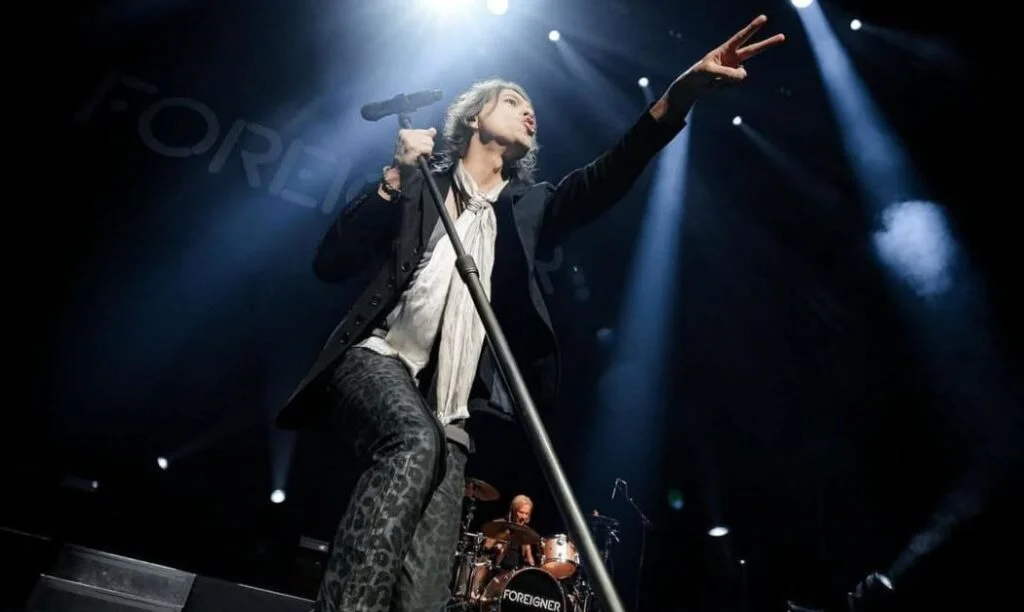A band member of the band Foreigner performing on stage.