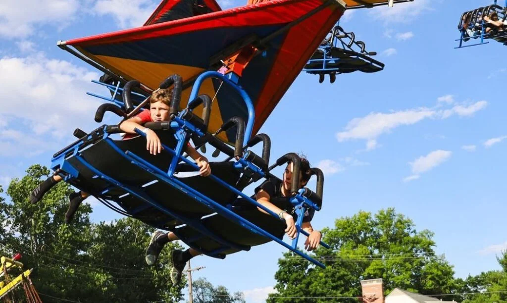 Young kids enjoying a thrill ride at a local fair