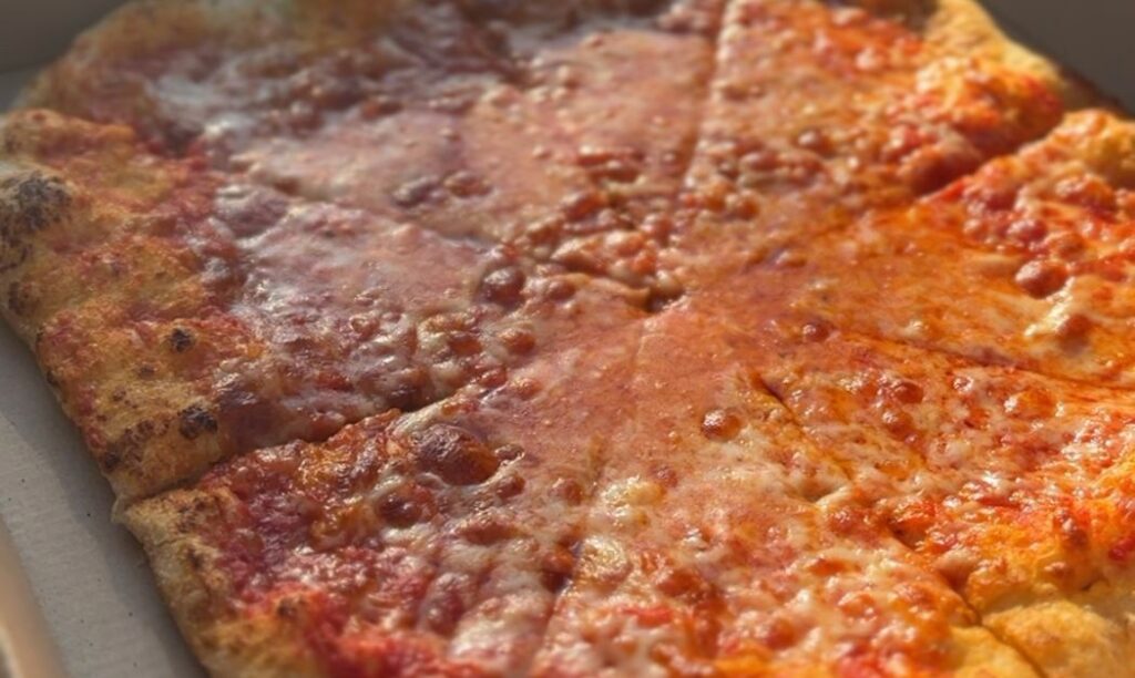 A full cheese pizza glowing in the sun at Artisan Pizza Cafe in Columbus, OH.