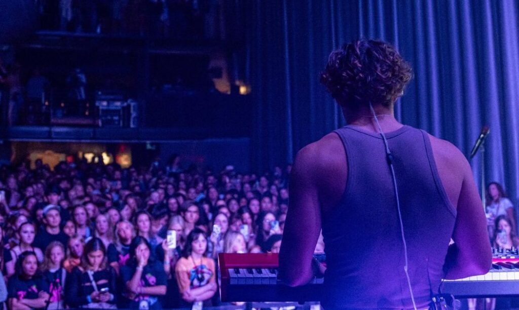 Benson Boone playing a keyboard at a show.