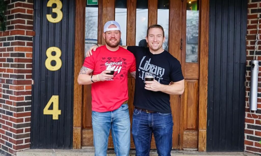 Two men pose outside of Zeno's in Harrison West.