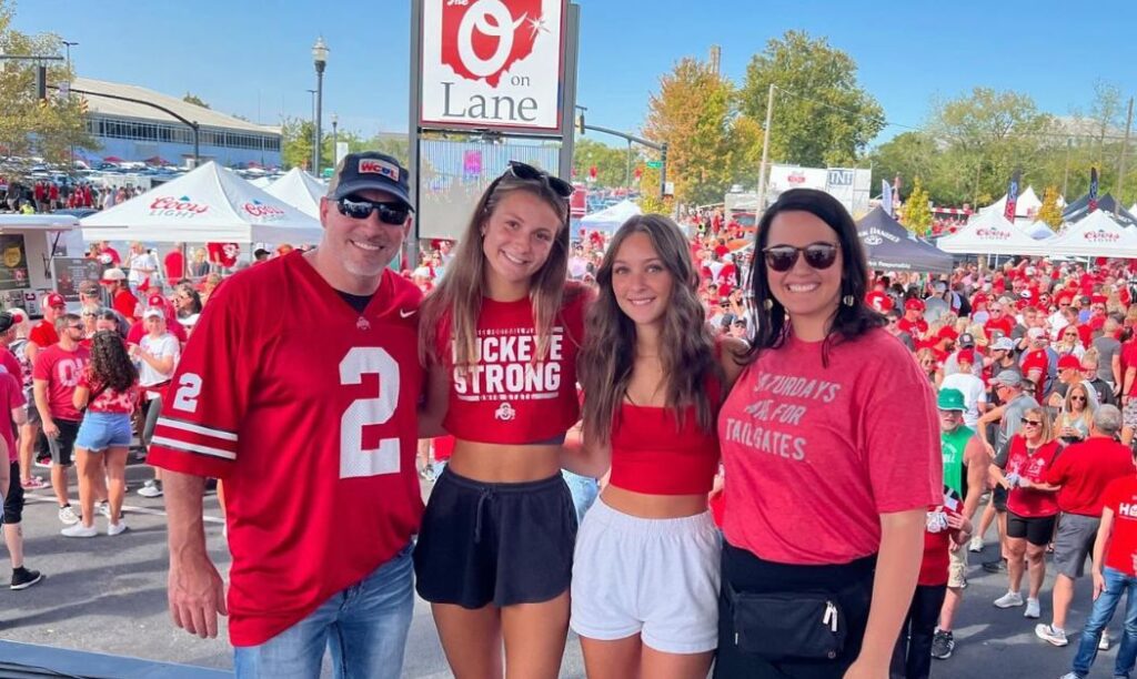 People posing on a stage during an outdoor tailgate at The O on Lane. 