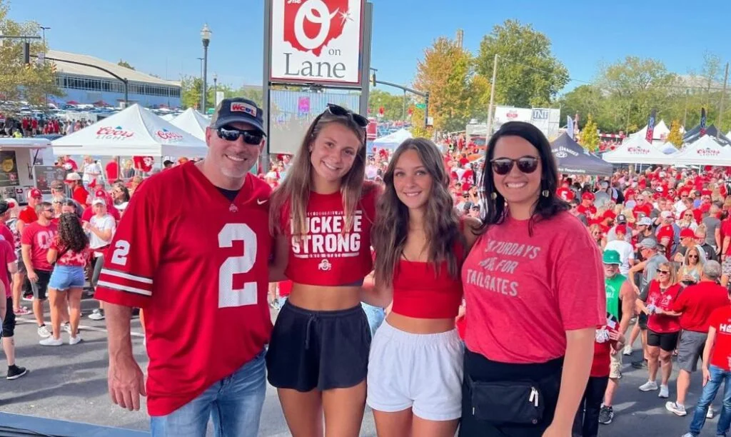 People posing on a stage during an outdoor tailgate at The O on Lane. 