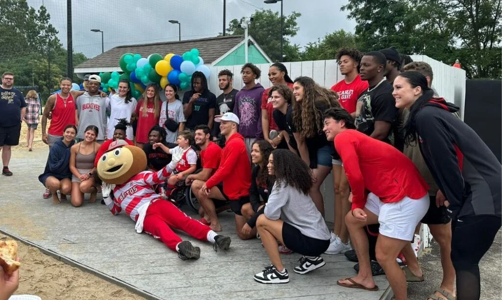 People posing with Brutus Buckeye at Woodlands Backyard.