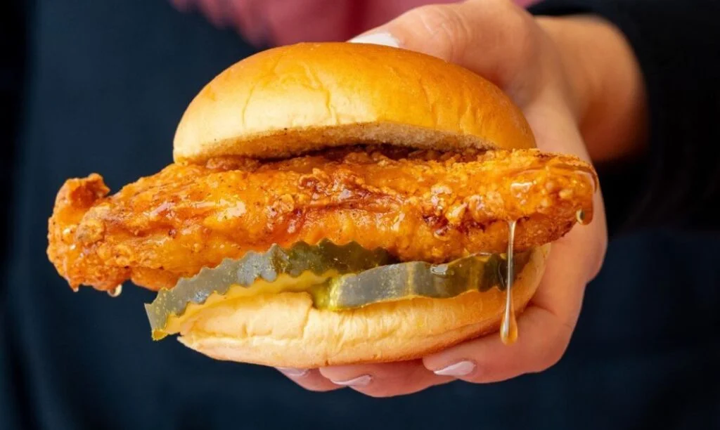 A Chicken sandwich with pickles dripping with honey