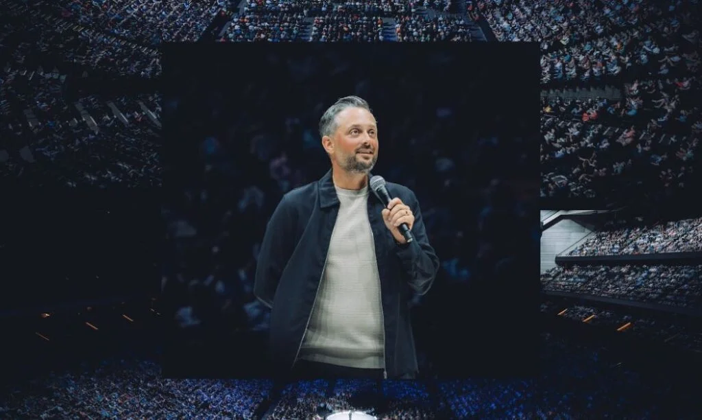 Comedian Nate Bargatze performs in front of a large arena audience.