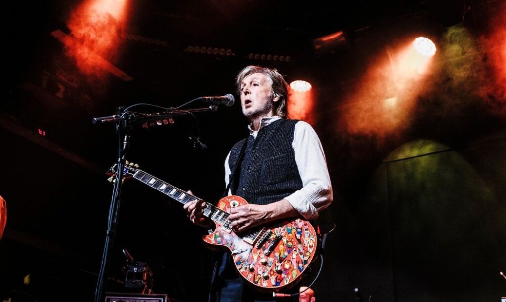 Paul McCartney performing on stage with his signature lefty guitar